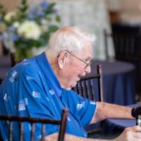 Side profile. of gGenentleman with white hair and blue shirt sitting at table